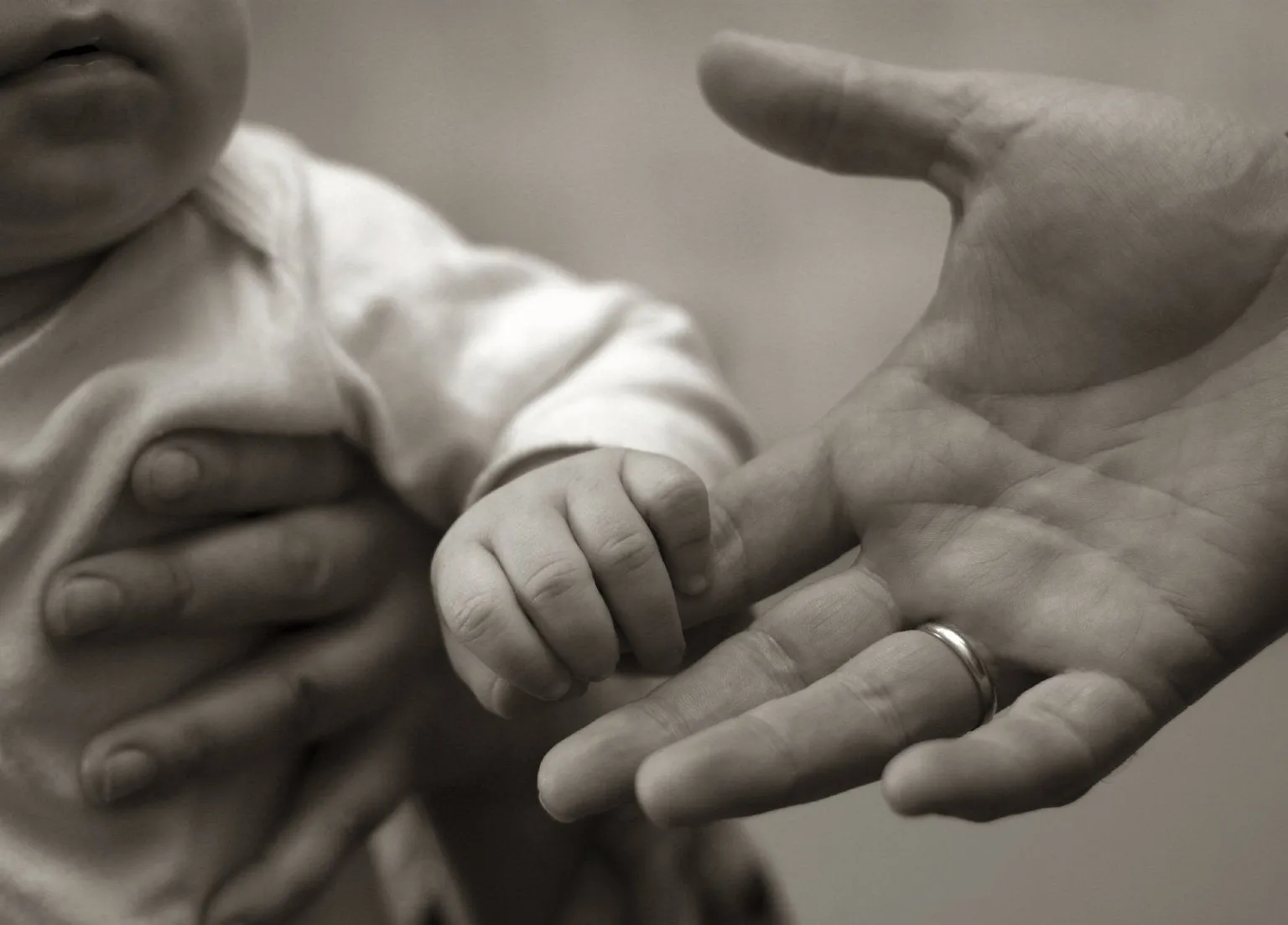 A baby's hand reaching toward an adult hand, suggesting learned responses and new patterns