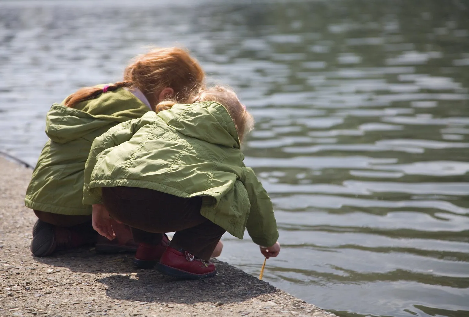 Two children crouching by the water, evoking curiosity and the inner child