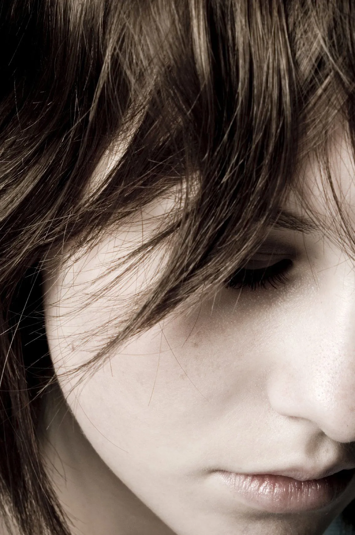 Close portrait of a woman looking down, suggesting anxious, inward thought