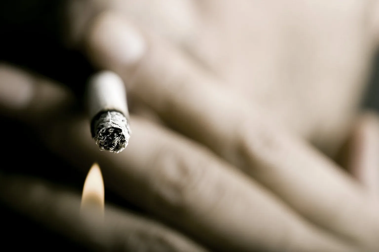 A hand holding a lit cigarette, illustrating smoking reduction and cessation