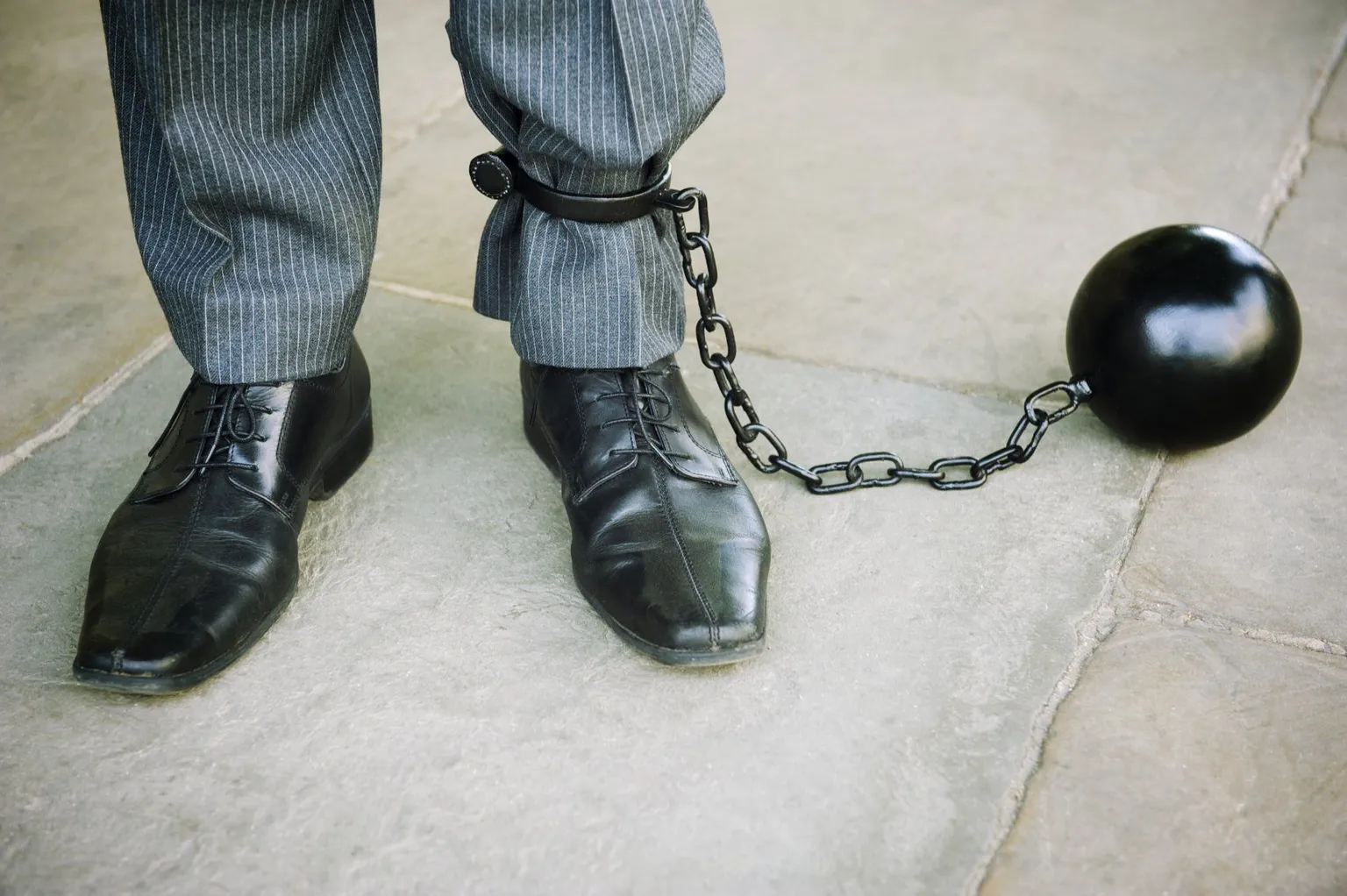 A person held back by a ball and chain, a metaphor for feeling trapped by stress